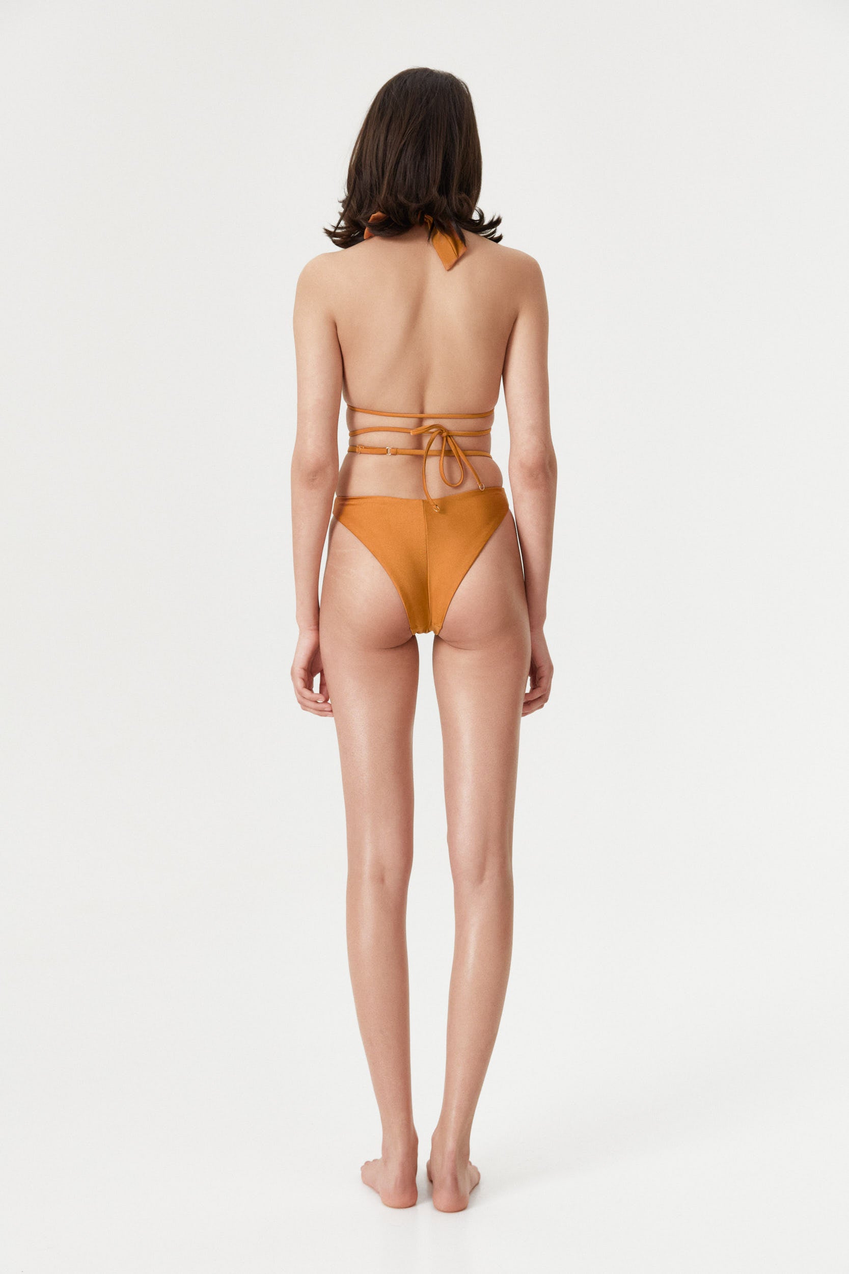 Rear view of the model in the Amber Infinity Bottom, emphasizing the flattering Brazilian coverage and adjustable waist.